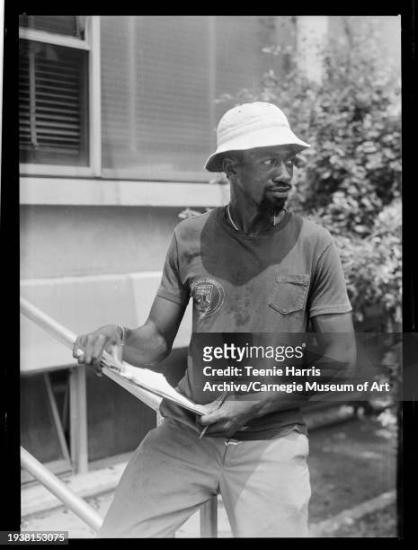 View of Schenley High School physical education instructor Fred Lucas as he stands, with a clipboard, outside of the University of Pittsburgh's Trees...