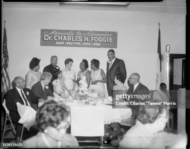 Group photo in Wesley Center AME Zion Church with American flag, and sign inscribed 'Moments to Remember Dr Charles H Foggie Our Pastor, 1944 -...