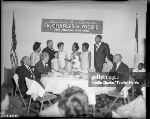 Group photo in Wesley Center AME Zion Church with American flag, and sign inscribed 'Moments to Remember Dr Charles H Foggie Our Pastor, 1944 -...