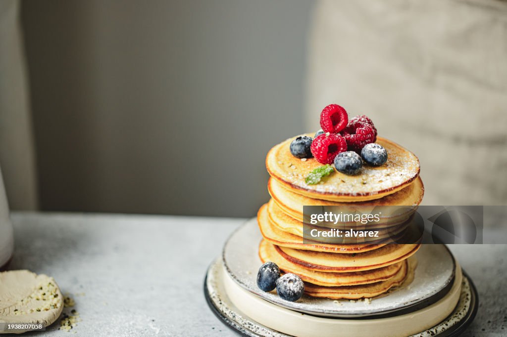 Stack of pancakes served with berries and sugar powder