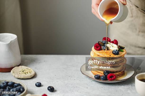 gros plan d’une femme versant du sirop d’érable sur des crêpes maison - stylisme culinaire photos et images de collection