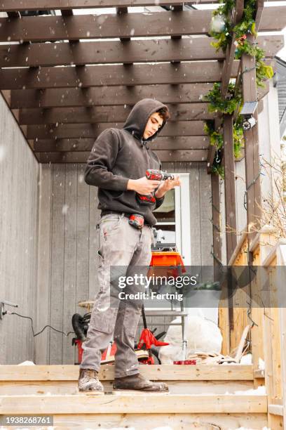 un joven trabajador de la construcción fuera de una casa residencial trabajando - tradesman fotografías e imágenes de stock