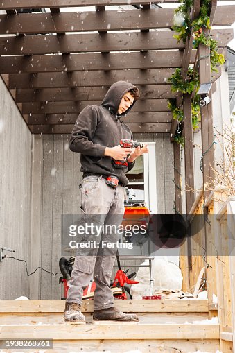 A young construction worker outside of a residential house working