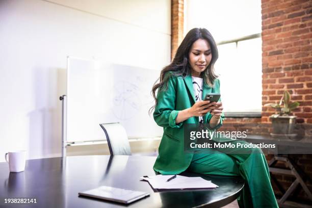 female businesswoman using smartphone in modern office conference room - front looking asian women stock pictures, royalty-free photos & images