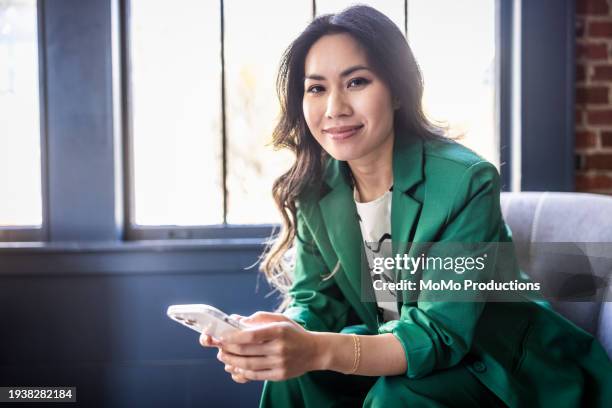 portrait of of young businesswoman using smartphone in modern office - aziatische etniciteit stockfoto's en -beelden