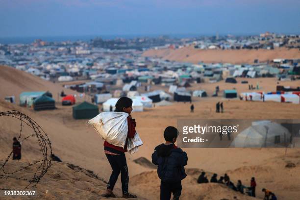 Displaced Palestinian children walk on a hill facing their makeshift camp in Rafah, on the southern Gaza Strip on the border with Egypt on January 19...