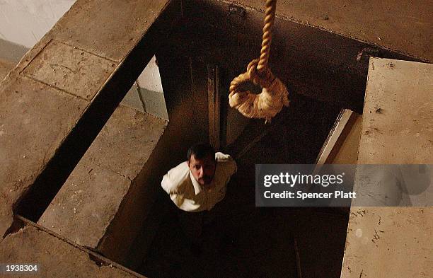 Man stands under a noose at the gallows of the infamous Abu Greib prison April 18, 2003 in Baghdad, Iraq. Thousands of people disappeared into the...