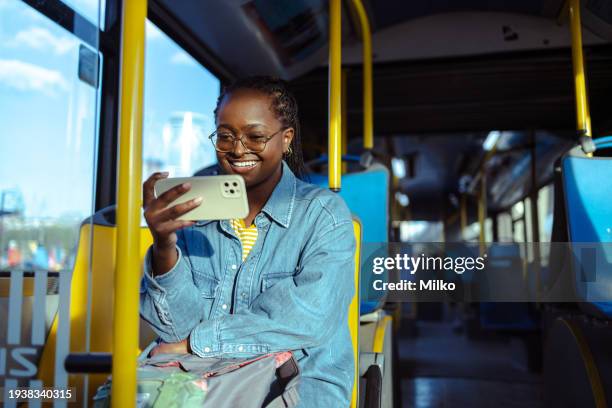 african american woman watching online content on smart phone in public transport - streaming service stock pictures, royalty-free photos & images