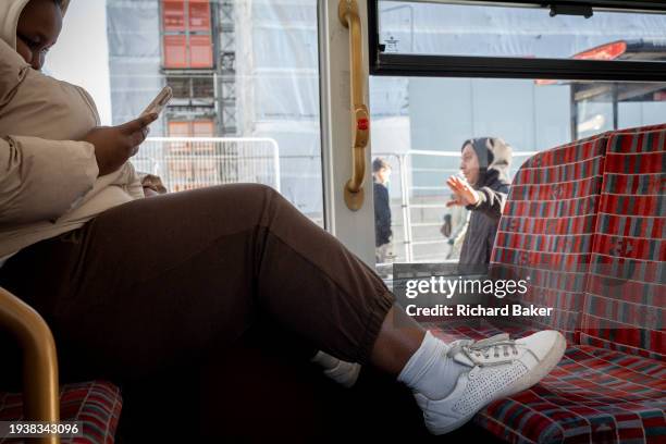 Woman passenger rests her shoes on the seats opposite of a London bus, on 18th January 2024, in London, England.