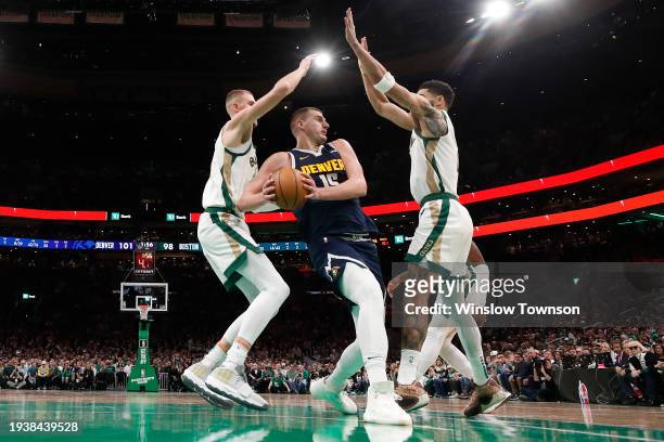 Nikola Jokic of the Denver Nuggets looks for a way past Kristaps Porzingis of the Boston Celtics and Jayson Tatum during the second half at TD Garden...