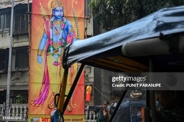 Woman talking on a mobile phone walks past a billboard displaying Hindu god Ram at a junction in Mumbai on January 20 ahead of the consecration...