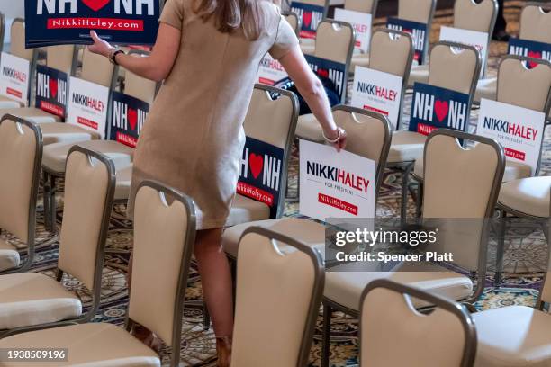 Campaign worker places signs on chairs before Republican presidential candidate Nikki Haley speaks at a campaign event in New Hampshire following her...