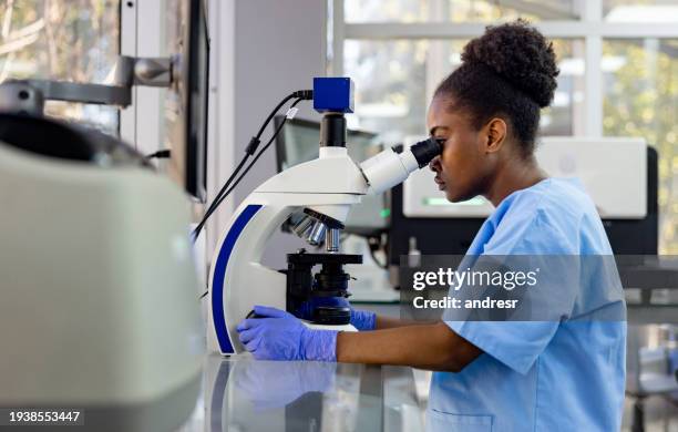pathologist looking at medical samples under the microscope at the lab - bacterie stockfoto's en -beelden