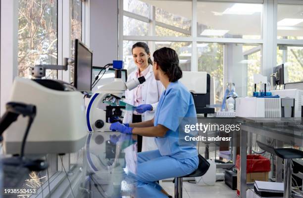 happy doctors working at the laboratory doing research and using a microscope - immunology stock pictures, royalty-free photos & images