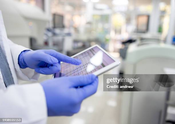 científico usando una aplicación móvil mientras trabaja en el laboratorio - laboratorio médico fotografías e imágenes de stock