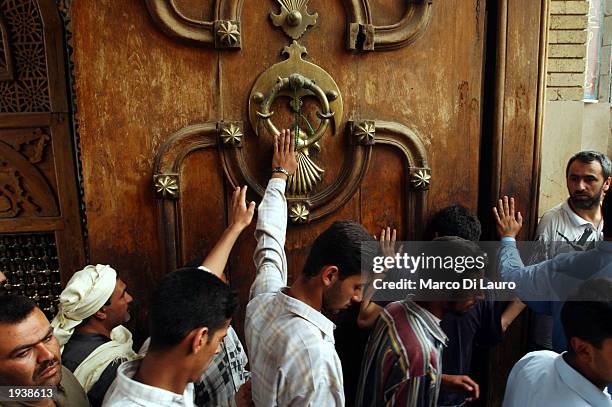 Muslim Shias touch the holy door of the Kadhimain Mosque as they leave Friday prayer April18, 2003 in Baghdad, Iraq. Most of Iraqi Muslims are either...
