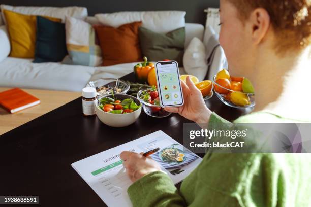 a woman is making a weekly nutrition plan and using mobile app - meal plan fotografías e imágenes de stock