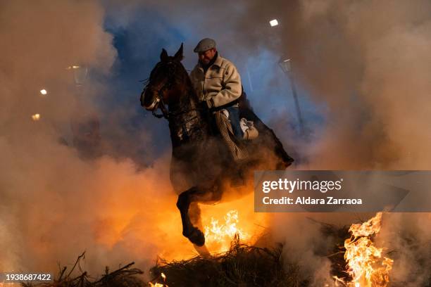 Man rides a horse through bonfires during 'Las Luminarias' Festival on January 16, 2024 in San Bartolome de Pinares, Spain. Each year, horses leap...