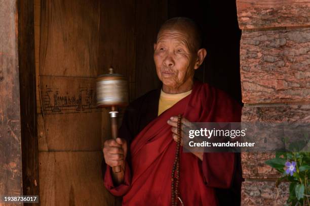 senior nun spins her prayer wheel in bhutan - bhutan stock pictures, royalty-free photos & images