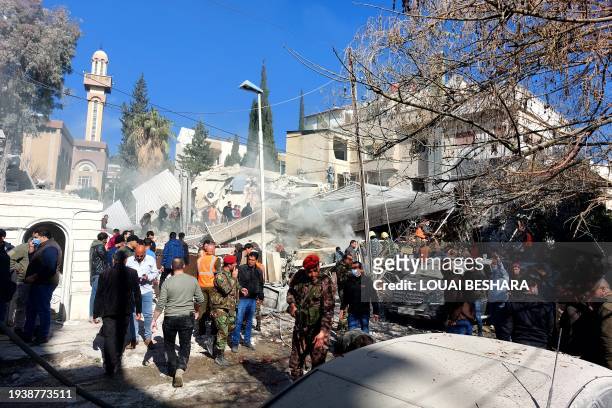 People and security forces gather in front of a building destroyed in a reported Israeli strike in Damascus on January 20, 2024. An Israeli strike on...