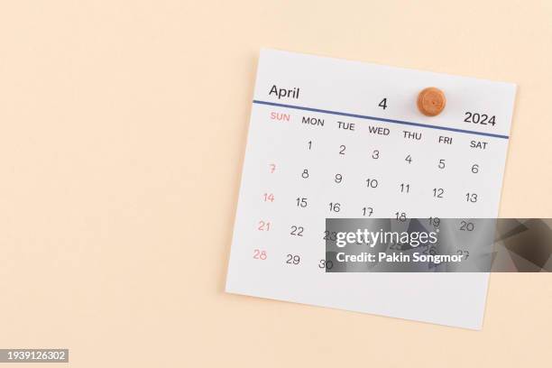 desk calendar 2024: april calendar is used to plan daily work and life with a push pin on a beige color paper background. - april stock pictures, royalty-free photos & images
