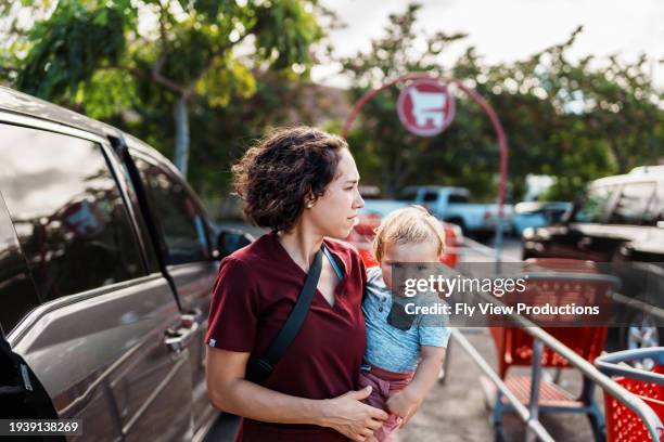 female nurse carrying baby son into grocery store after work - supermarket car park stock pictures, royalty-free photos & images