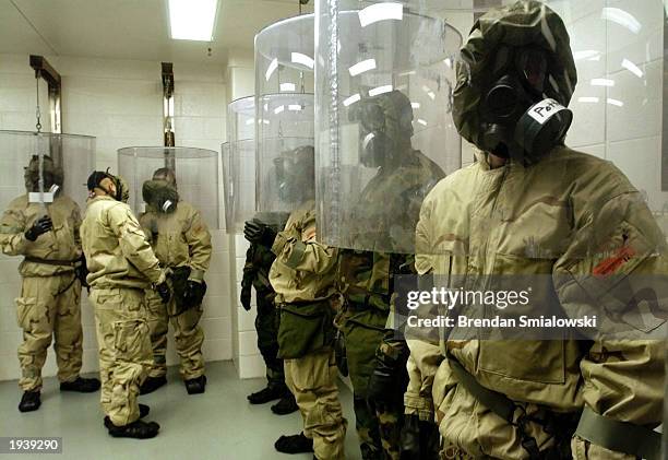 Soldiers wear gas masks while standing in an chemical school area known as the Hot Zone while they have the seal of their gas masks checked with...
