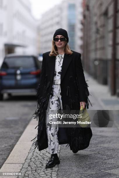 Sonia Lyson seen wearing Gucci black sunglasses, COS black wool knit beanie / hat, COS black oversized long wool coat with fringed details, Zara...