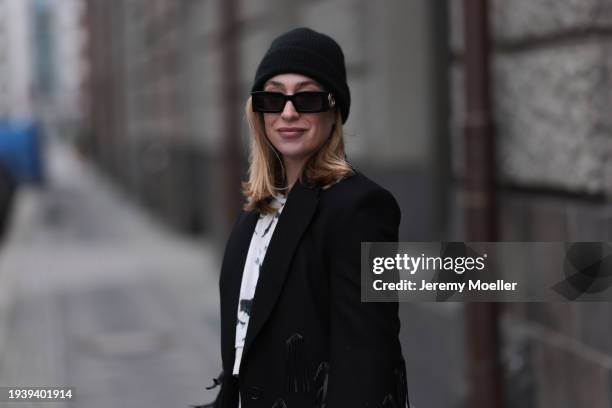 Sonia Lyson seen wearing Gucci black sunglasses, COS black wool knit beanie / hat, COS black oversized long wool coat with fringed details, Zara...