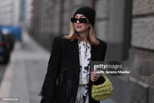 Sonia Lyson seen wearing Gucci black sunglasses, COS black wool knit beanie / hat, COS black oversized long wool coat with fringed details, Zara...