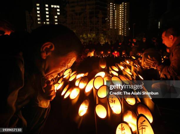 People pray for the victims in front of candle-lit bamboo lanterns at the memorial ceremony on the 29th anniversary of the Great Hanshin Earthquake...