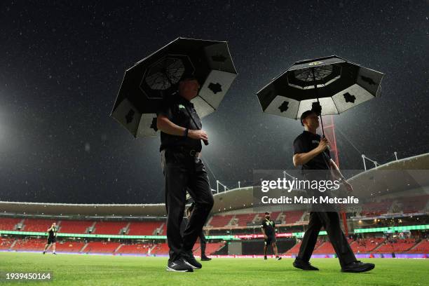 Umpires walk from the field after inspecting the pitch before abandoning the match during the BBL match between Sydney Thunder and Melbourne...