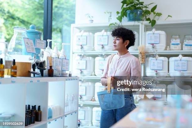 woman shopping personal care in refill store - prodotto per le pulizie foto e immagini stock