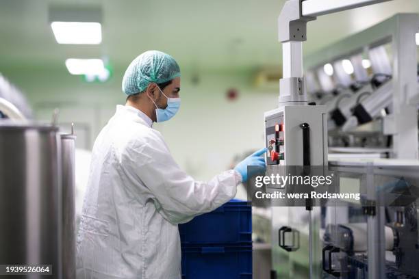 lab technician controlling automatic medicine compounding machine in clean room - arzneimittelherstellung stock-fotos und bilder