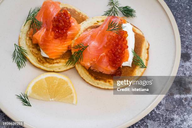 blinis with smoked salmon, white cheese, red caviar, garnished with dill - räucherlachs stock-fotos und bilder