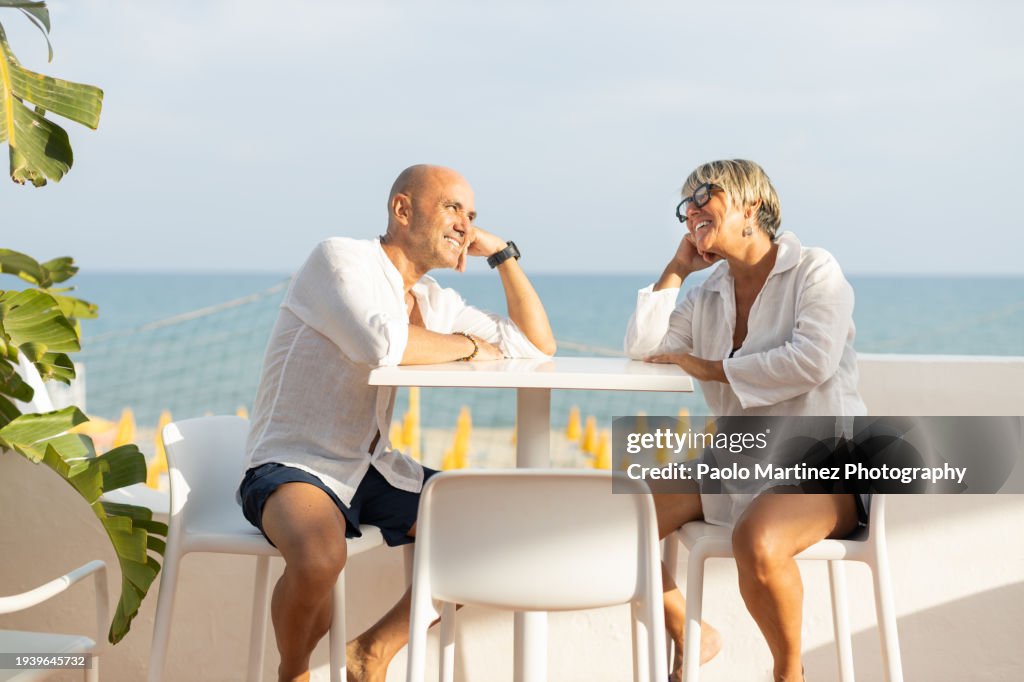 Couple sitting at patio beach cafe by the sea