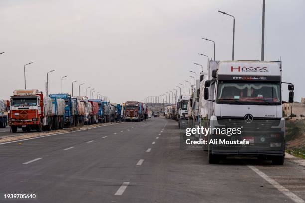 Trucks carrying aid in front of the Rafah crossing await entry into the Gaza Strip after the Security Council's decision to increase the entry of aid...