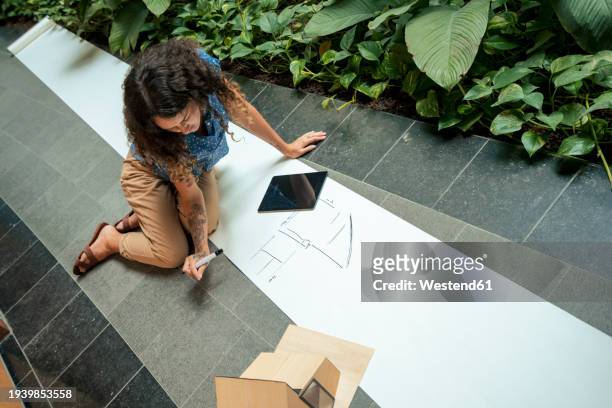 young architect examining drawing on blueprint in office - pen mockup stock-fotos und bilder