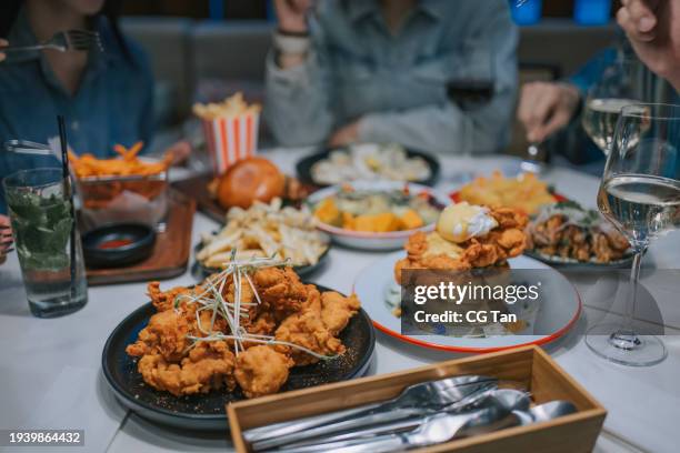 close up comfort food on dining table in social gathering with friends at restaurant - gefrituurde kip stockfoto's en -beelden