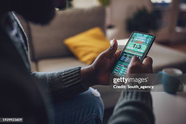 hombre absorto en apuestas deportivas en vivo en un teléfono inteligente - juegos fotografías e imágenes de stock