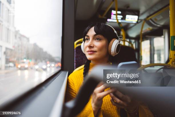 thoughtful woman sitting with smart phone in bus - looking out bus window stock pictures, royalty-free photos & images