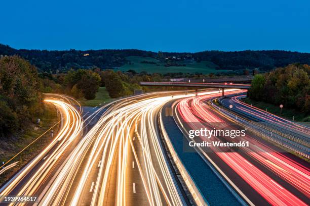 germany, baden-wurttemberg, leonberg, vehicle light trails stretching alongbundesautobahn8 at dusk - autobahn stock pictures, royalty-free photos & images