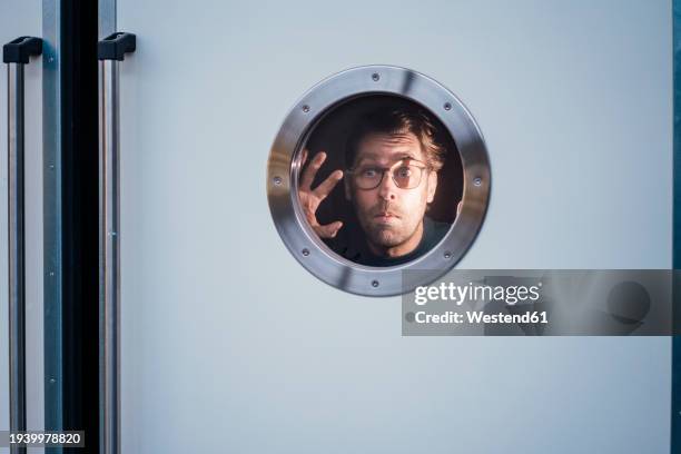 shocked businessman looking through peephole - bullauge stock-fotos und bilder