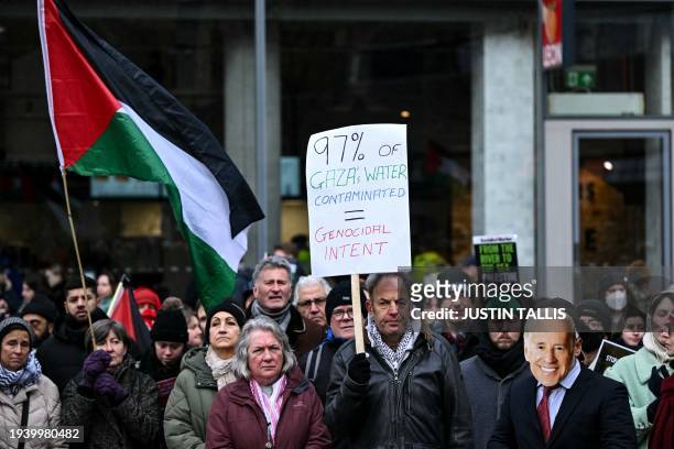 Pro-Palestinian supporters including one wearing a mask depicting US President Joe Biden , hold placards and chant slogans as they take part in a...