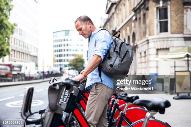 businessman standing near electric bicycle at street - commuter man europe bike stock pictures, royalty-free photos & images