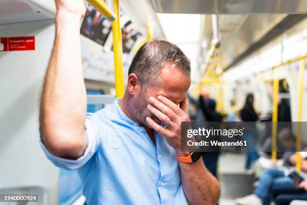 tired businessman commuting through train - rubbing eyes stock pictures, royalty-free photos & images