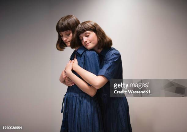 smiling twin sisters supporting and consoling each other - identical twin stock pictures, royalty-free photos & images