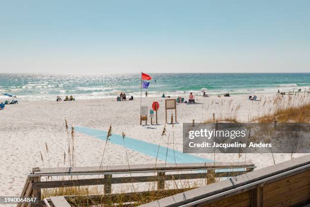 view of the sea from the wooden walkway that leads over the dunes to the beach and a blue rubber mat for easier access to the beach, henderson beach state park, destin, florida,  usa - florida v florida state stock pictures, royalty-free photos & images