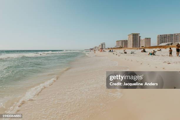 view of the almost empty beautiful and super wide beach, in the background a few condo and apartment buildings, henderson beach state park, destin, florida, usa - destin beach stock-fotos und bilder