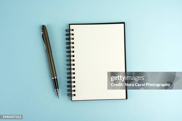 blank notepad and pen on blue background - bloco espiral imagens e fotografias de stock